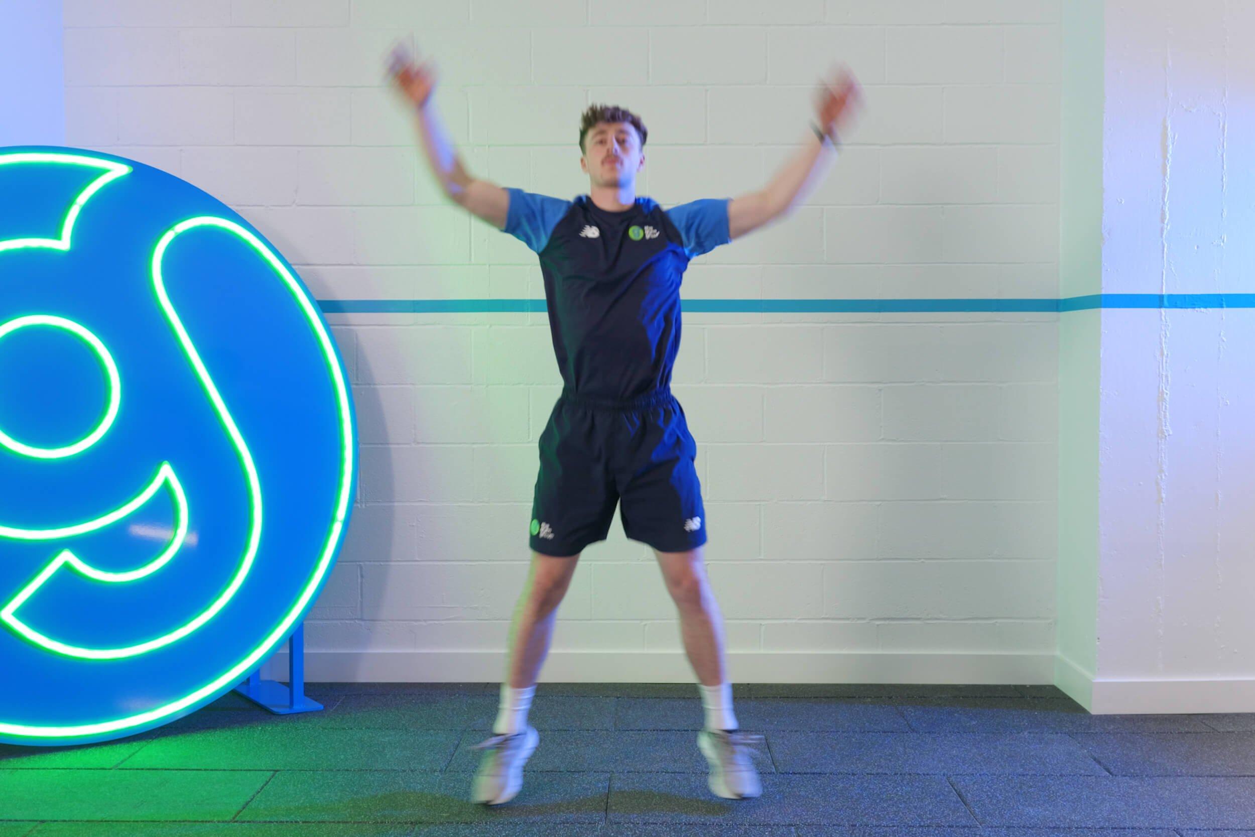 Personal Trainer demonstrating how to do jumping jacks.