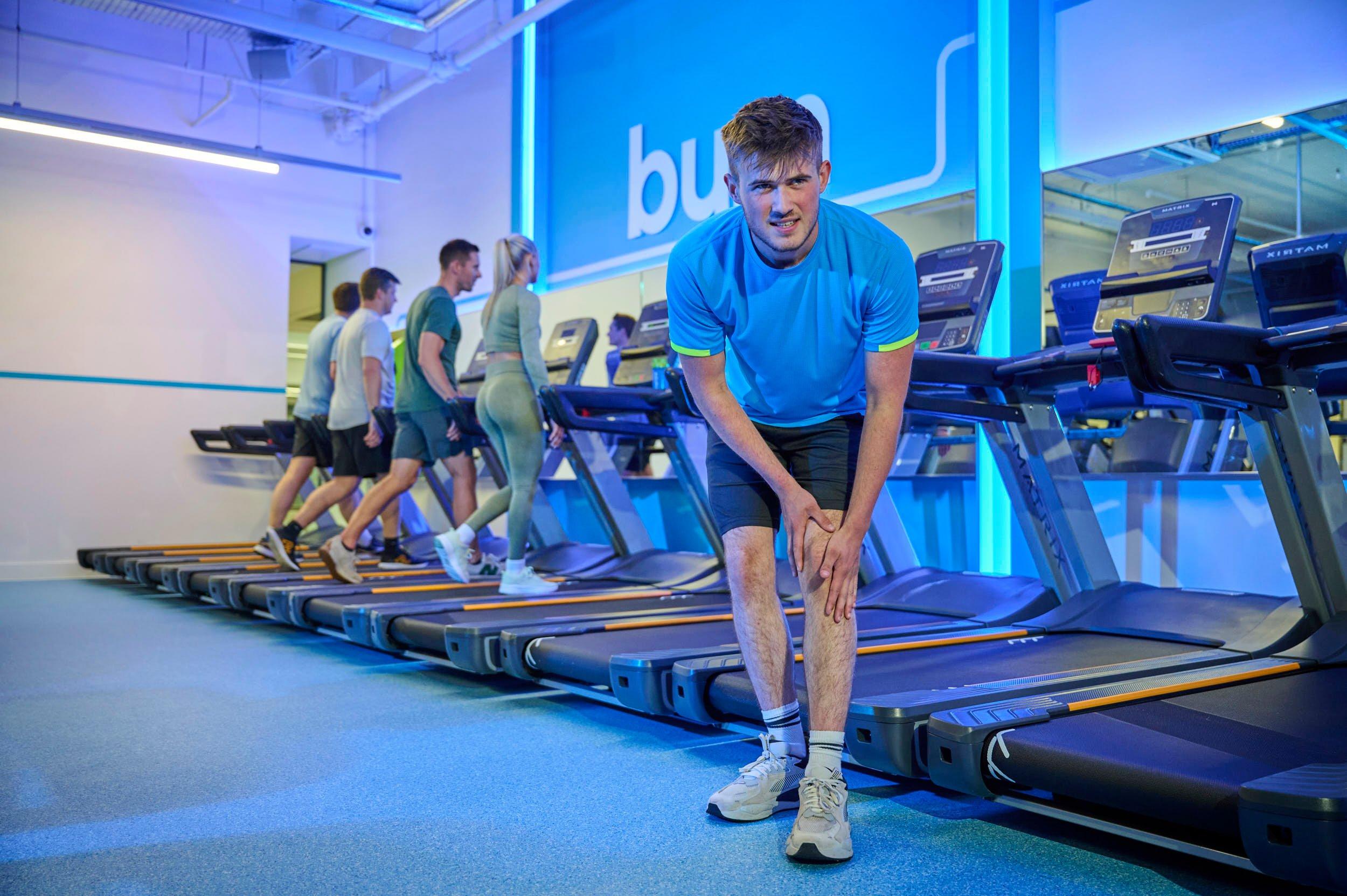 Gym member stretching his calf to accelerate his muscle recovery from an injury.