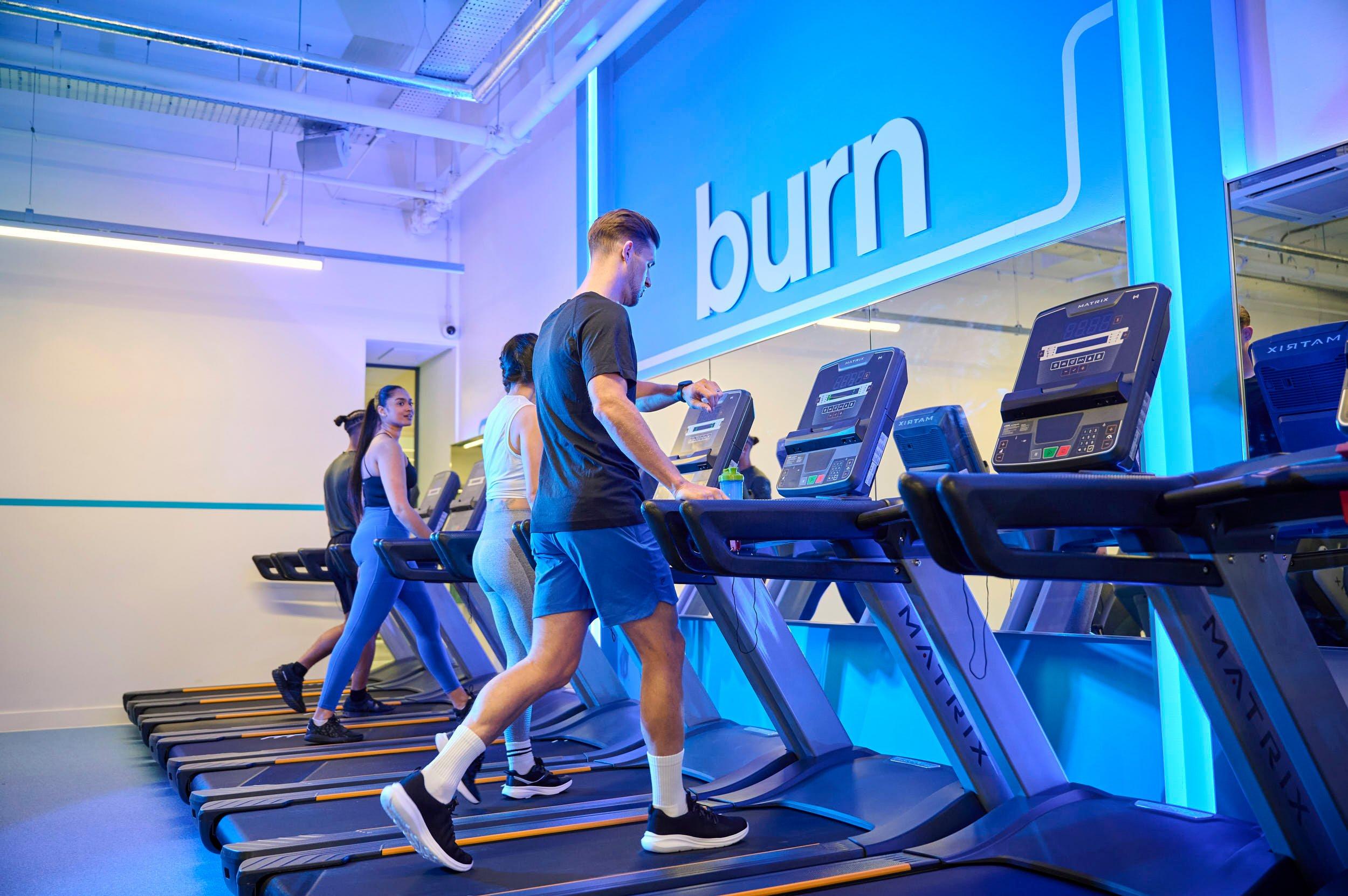 Gym members walking on treadmills.