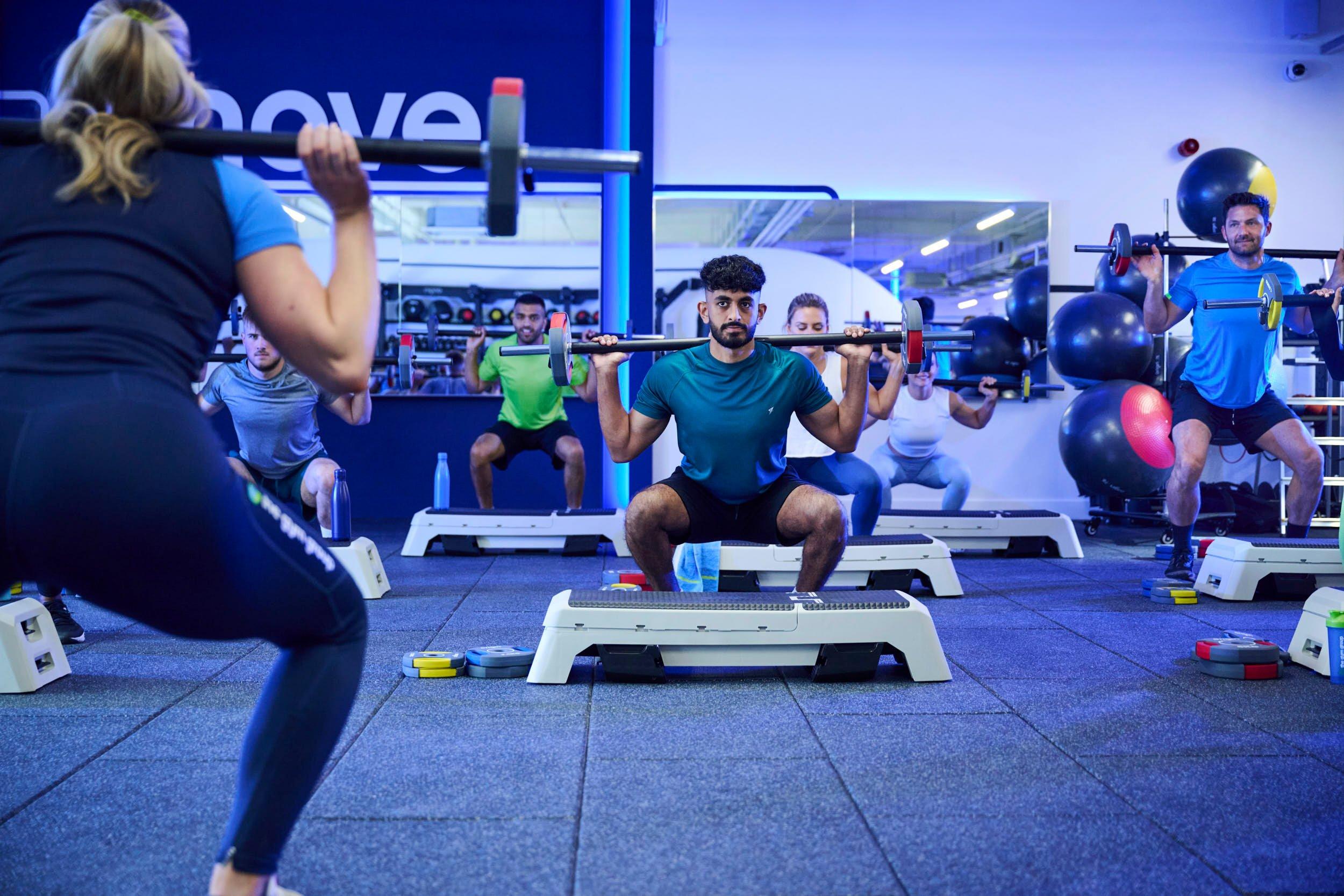 member doing barbell squats at a gym class