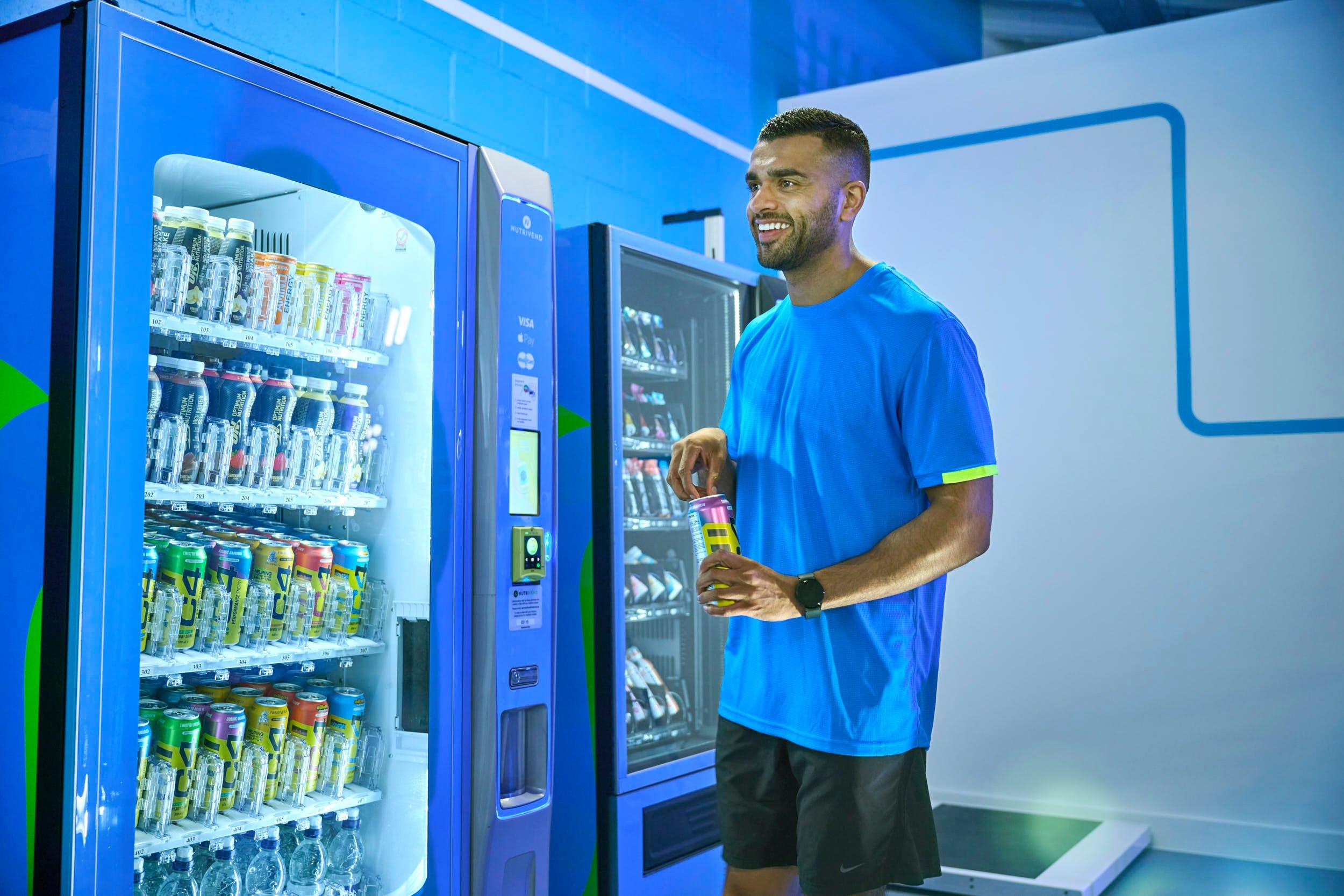 Gym member getting an energy drink from vending machine.