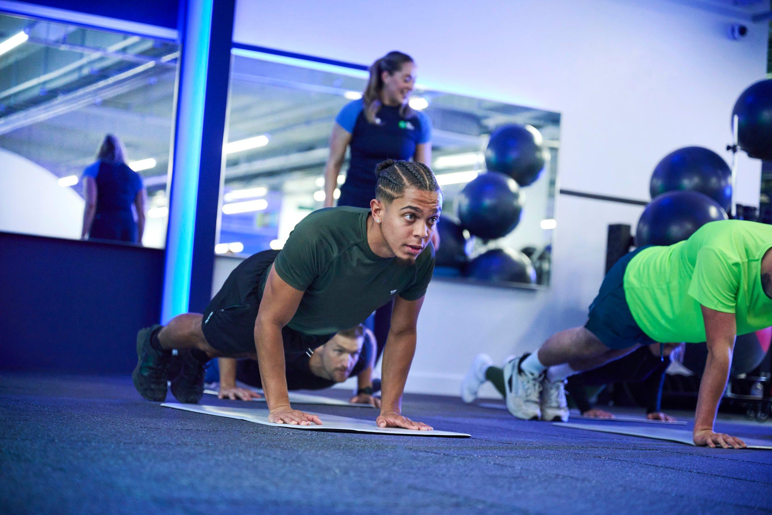 Gym members doing push ups together.