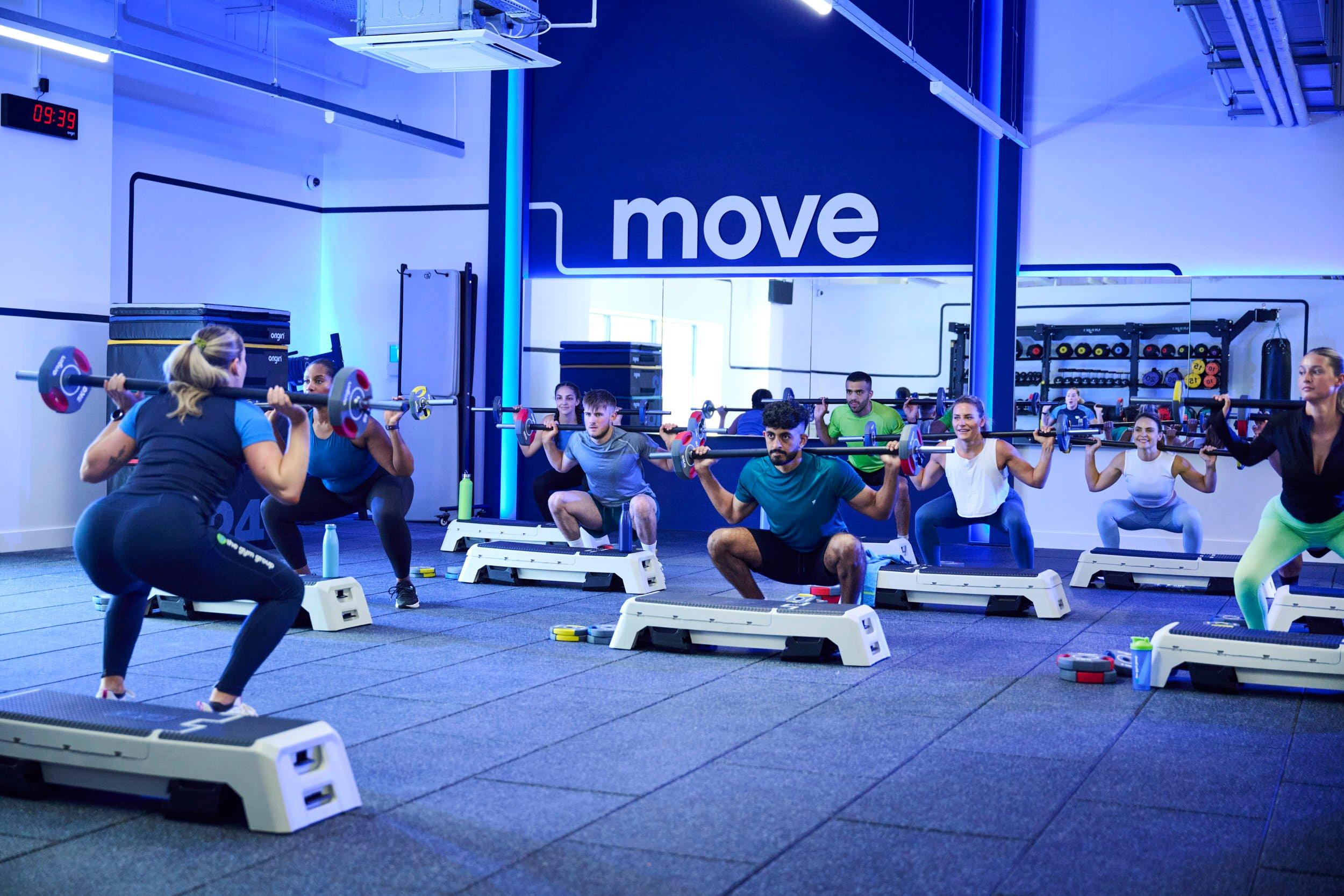 Personal trainer showing a group exercise class howe to squat.