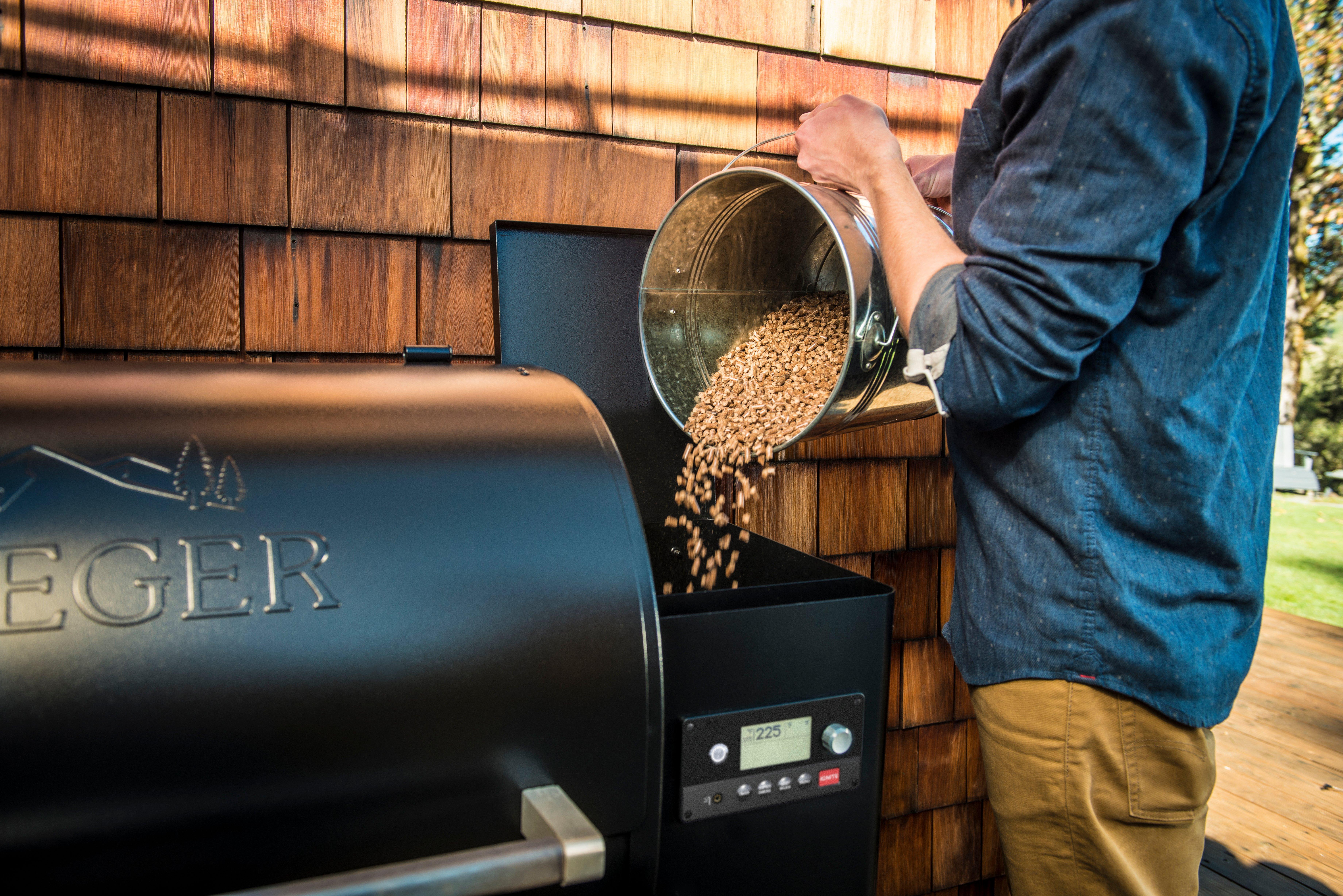 Man adding pellets to a Traeger Wood Pellet grill hopper