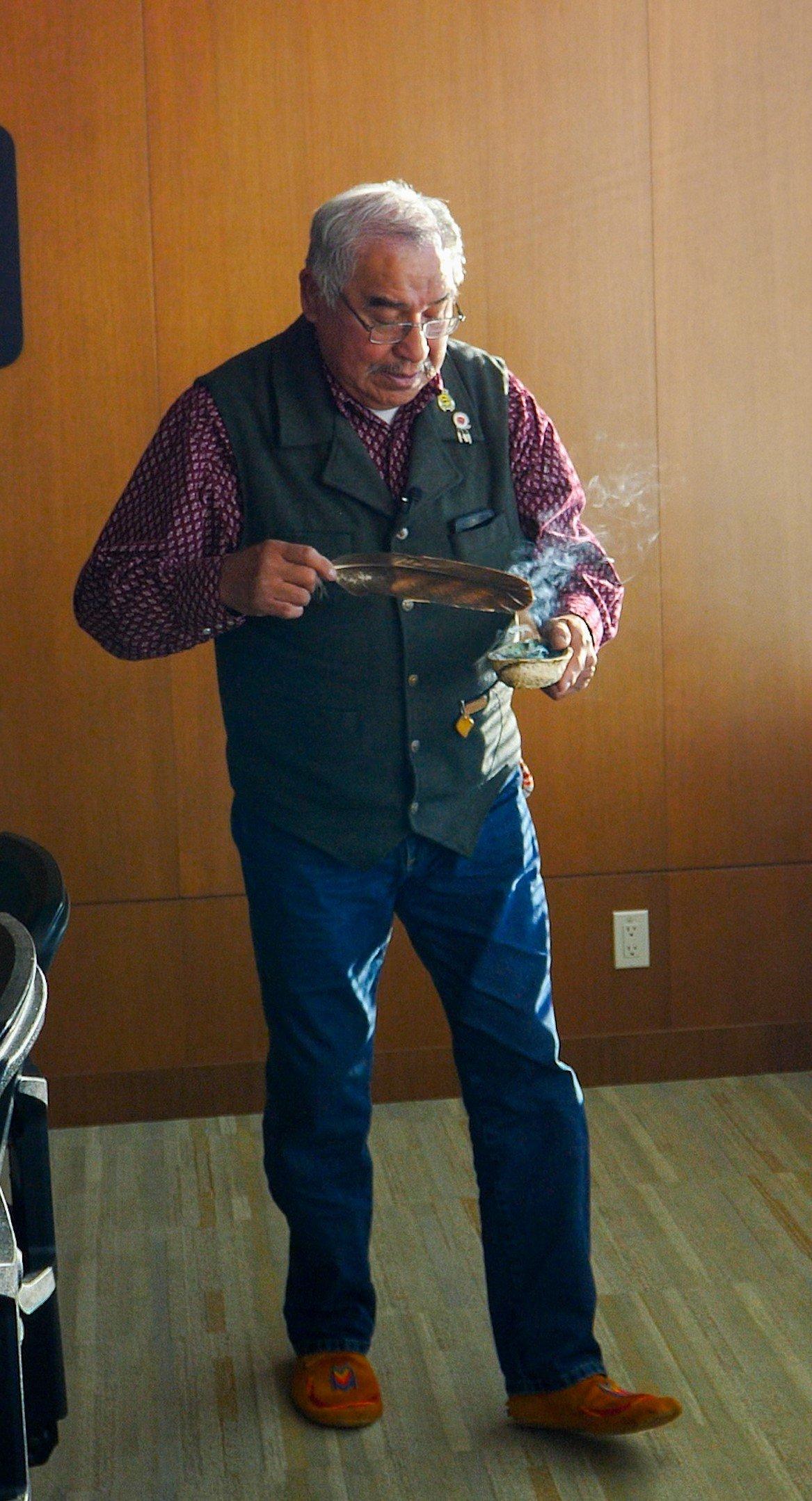 Elder Clarence Wolfleg smudges the Sohkyoyiis room at UFAs Calgary Support Office