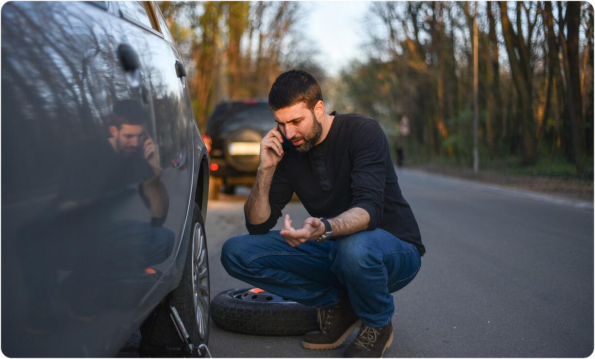 Driver on the phone next to their vehicle after a breakdown