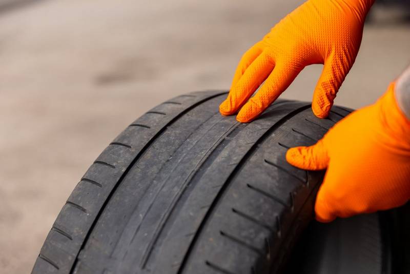 Gloved hands checking the tread on a worn tyre