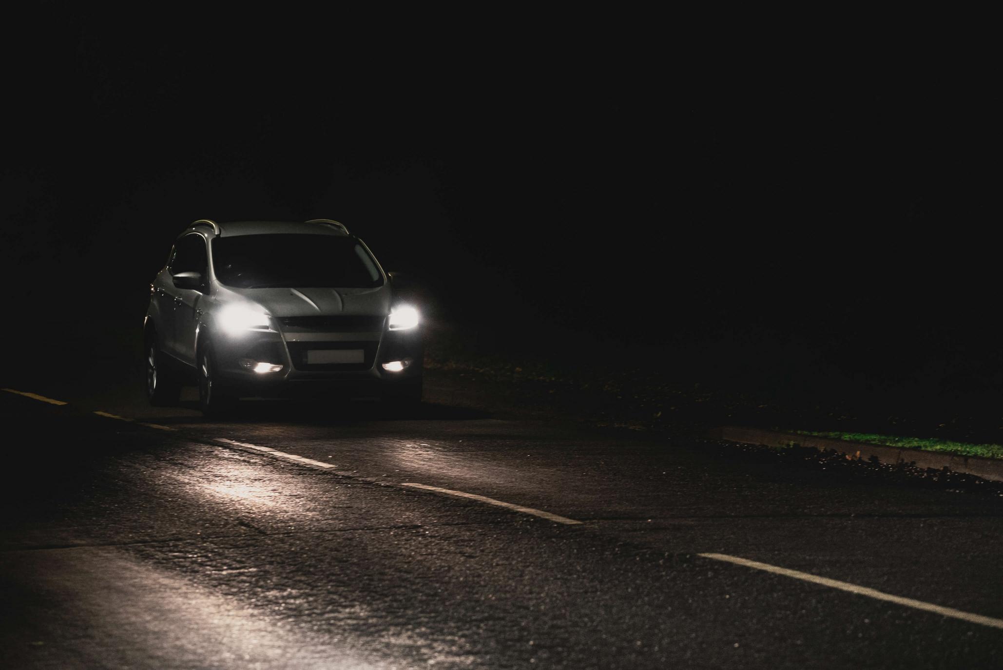 car driving in the dark with headlights on