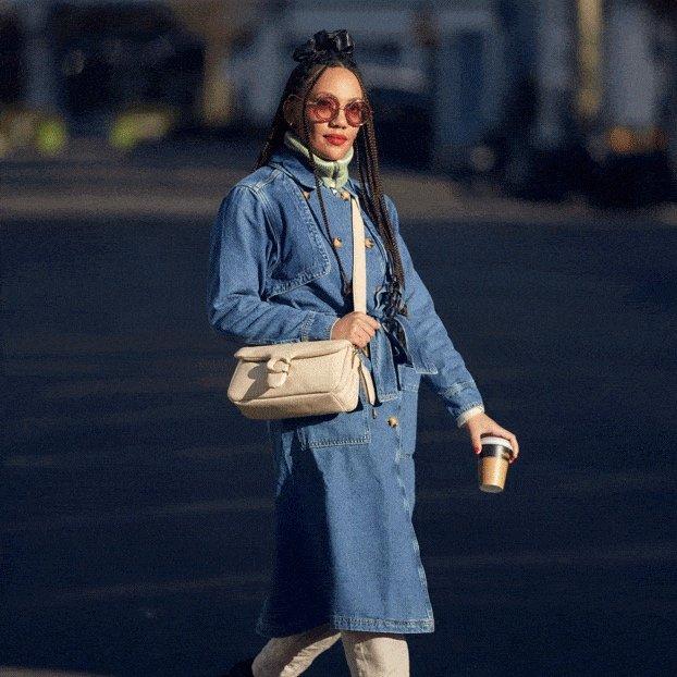 a woman in a blue denim coat walking down the street