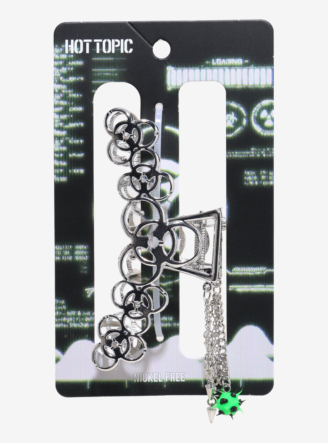 Silver biohazard-motif claw hair clip on a printed retail card